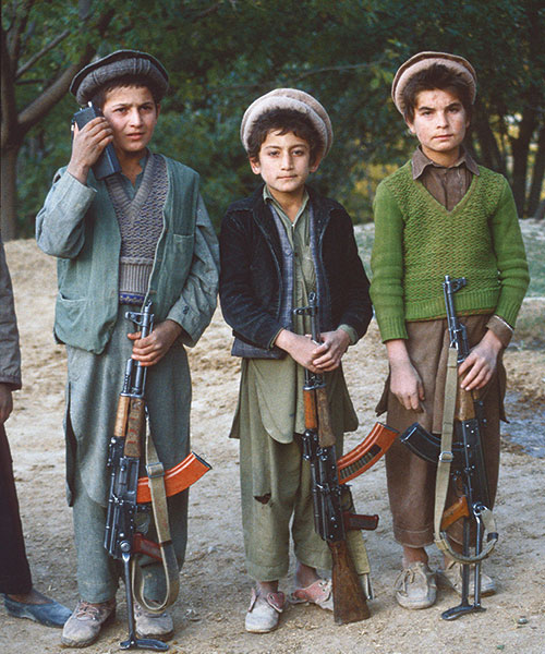 Tre barn som står på rekke med hvert sitt gevær.