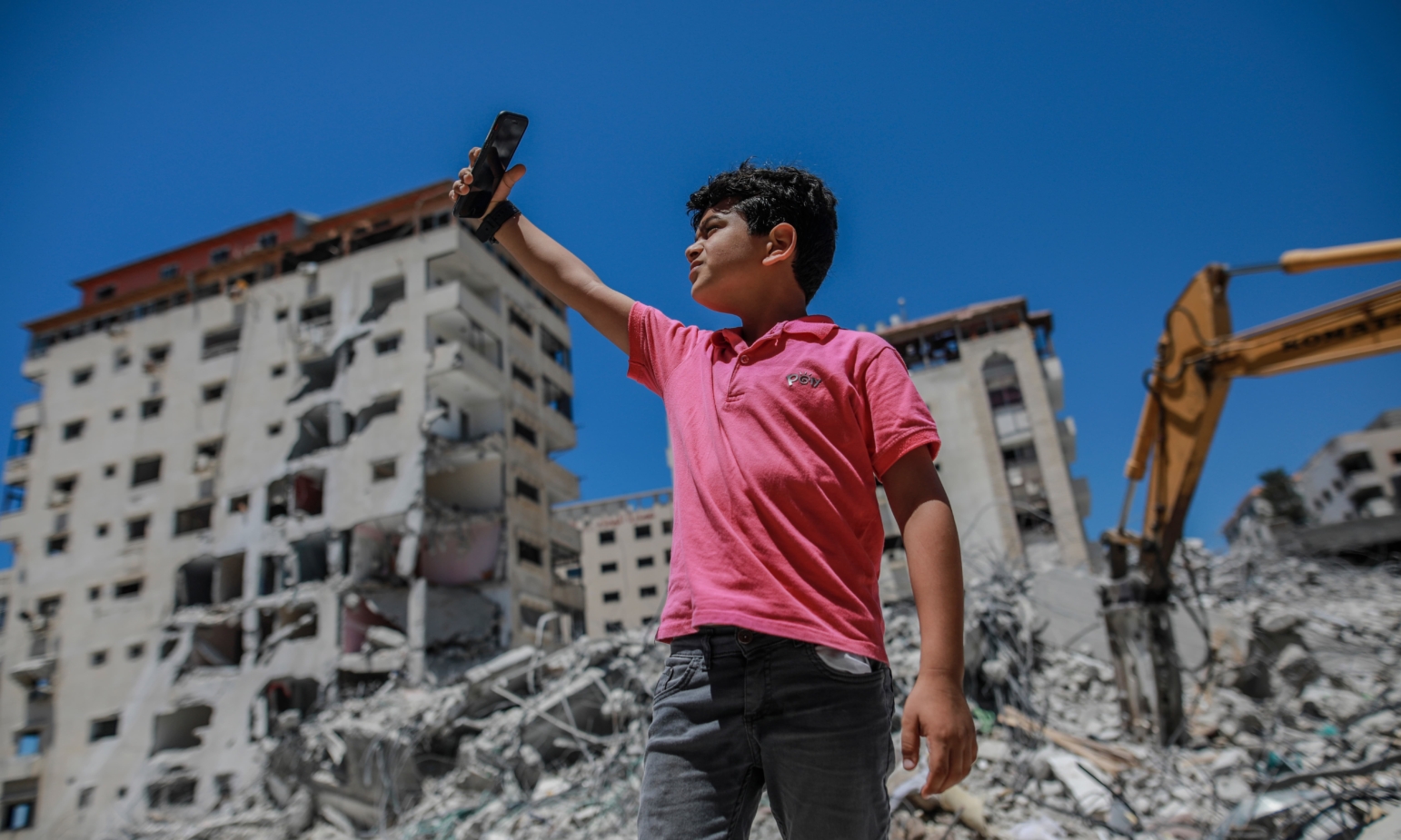 Ung gutt tar selfie på Gaza foran ødelagte bygninger
