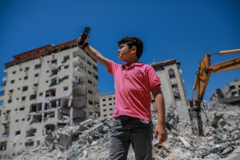 Ung gutt tar selfie på Gaza foran ødelagte bygninger
