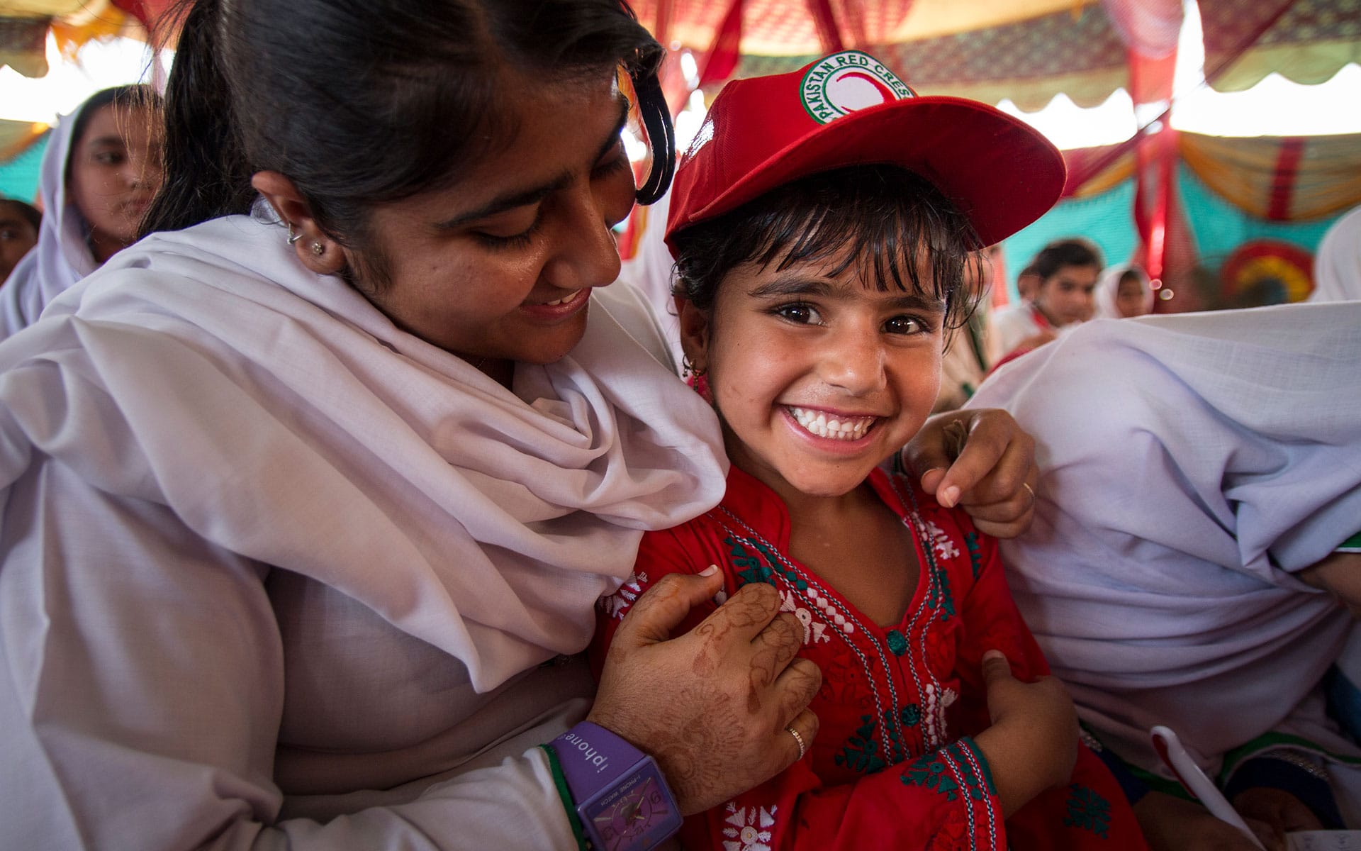 Kvinne holder rundt en ung jente som smiler til kamera