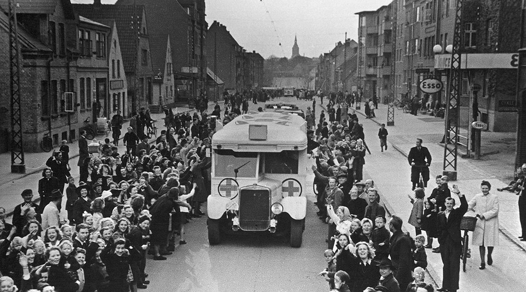 En hvote bussen med røde kors kjører gjennom en jublende folkemengde