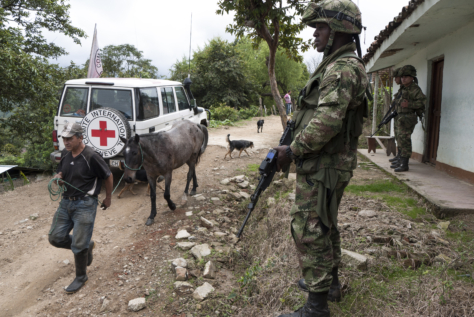 Soldater vokter et hus mens en mann leier et esel forbi. Man ser også en Røde Kors bil i bakgrunnen