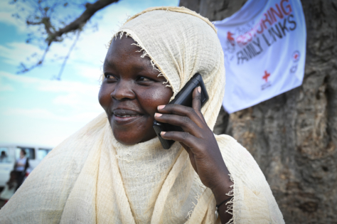 En ung kvinne i hvit hijab snakker i telefonen mens hun smiler.