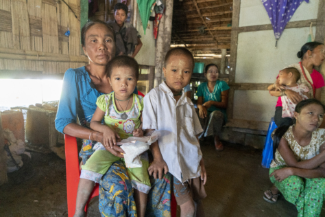 En mor sitter på en stol med datteren sin på fanget. Sønnen står ved siden av. Alle tre ser alvorlig i kameraet.